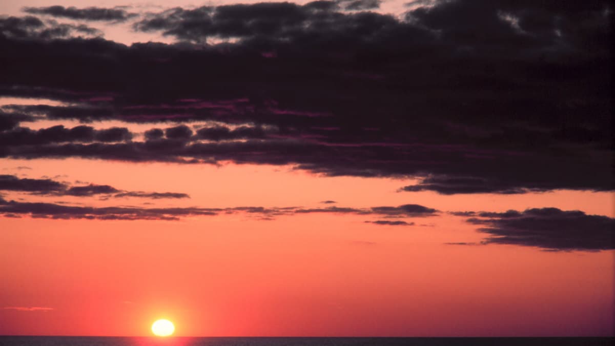 Orange and red sunset light across clouds near the horizon.
